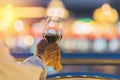 Hand holding and toasting a glass of red wine at night with light bokeh Romantic or celebration for concept Royalty Free Stock Photo