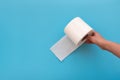 Hand holding toilet paper rolls on blue background. Copy space Royalty Free Stock Photo