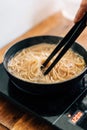 Hand holding tong stir spaghetti pasta In boiling hot water in steel pan. Preparation for making Al Dente Spaghetti