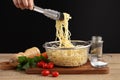 Hand holding tongs and cooked spaghetti from metal colander