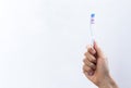 Hand holding a toothbrush on gradient background