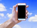 Hand holding touch screen mobile phone isolated on cloudy blue sky Royalty Free Stock Photo