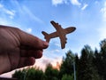 Hand holding toy wooden airplane plane and blue sky with forest background. The concept of flying on an airplane, travel Royalty Free Stock Photo