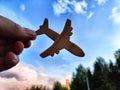 Hand holding toy wooden airplane plane and blue sky with forest background. The concept of flying on an airplane, travel Royalty Free Stock Photo