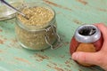 A hand holding a traditional Yerba mate vessel, next to a jar full of Paraguayan holly used to brew the drink