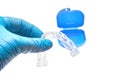 Hand holding transparent individual dental tray for teeth whitening in front of the dental container