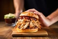 hand holding a turkey smoky barbecue sandwich over a wooden table