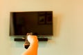 Hand holding TV remote control in front of widescreen TV set with blank screen. Royalty Free Stock Photo