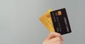 Hand is holding two credit card in black and gold color isolated on grey background Royalty Free Stock Photo