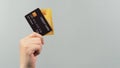 Hand is holding two credit card in black and gold color isolated on grey background Royalty Free Stock Photo