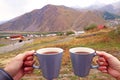 Hand Holding Two Cups of Hot Coffee with View of Stepantsminda Town of Georgia Royalty Free Stock Photo