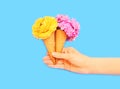 Hand holding two ice cream cone with flowers over blue Royalty Free Stock Photo