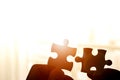 Hand holding two pieces of jigsaw connecting couple puzzle against sunrise effect Royalty Free Stock Photo