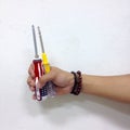 a hand holding two screwdrivers against a white wall background Royalty Free Stock Photo