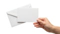 A hand holding two unsealed white envelopes against a plain background Royalty Free Stock Photo