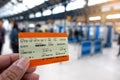 Hand holding UK Rail Return Ticket in Brighton & Hove train station