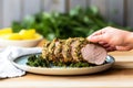 hand holding up a plate with herb crusted pork loin