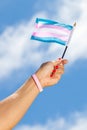 Hand holding up Transgender pride flag towards the sky