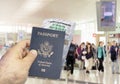 Hand holding a US passport with a wrinkled paper Coronavirus Covid 19 immunity certificate blurred airport in the background