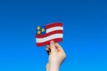 A hand holding USA symbolic flag. USA Strong Nation. Patriotism. Clear blue sky background