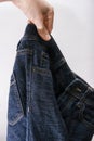 A hand holding used bluejeans on white background, second hand clothes concept Royalty Free Stock Photo