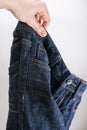 A hand holding used bluejeans on white background, throwing away of old shabby clothes Royalty Free Stock Photo