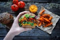 Hand holding vegan sweet potato black bean burger. Plant based food concept Royalty Free Stock Photo