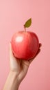 hand holding a vibrant red apple against a clean and minimalist background.