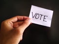 Hand holding a vote written paper note in election