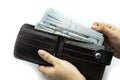 Hand holding wallet on bundles of 100 US dollars banknotes