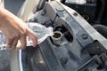 Hand holding water bottle is pouring water into the car radiator Royalty Free Stock Photo