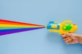 Hand holding water gun spray out with colorful cutting paper