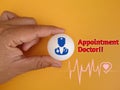 Hand holding white ball with doctor icon, heart beat icon and text Appointment doctor on background