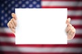 Hand holding white blank paper sheet mockup with US flag blurred Royalty Free Stock Photo