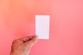 Hand holding white blank price label tag on pink background. Royalty Free Stock Photo