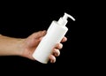 Hand holding a white bottle of liquid soap. Close up. Isolated on black background Royalty Free Stock Photo