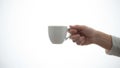A hand is holding a white ceramic cup against a light plain background Royalty Free Stock Photo