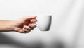 A hand is holding a white ceramic cup against a plain white background Royalty Free Stock Photo