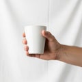 A hand is holding a white ceramic cup against a plain white background Royalty Free Stock Photo