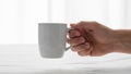 A hand holding a white ceramic mug against a plain background Royalty Free Stock Photo