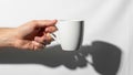 A hand holding a white ceramic mug against a plain white background Royalty Free Stock Photo
