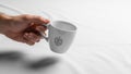 A hand holding a white ceramic mug with a simple black leaf design Royalty Free Stock Photo