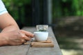 Hand holding white cup of hot espresso coffee on wooden table at the outdoor cafe in the morning light with copy space Royalty Free Stock Photo