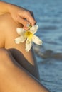 Hand holding white flower on the white sand beach and blue aqua sea background. vertical photo