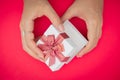 Hand holding white gift box, Used for New Year`s Eve, Christmas, Birthday, Valentine`s Day. on redbackground