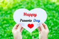 Hand holding white heart paper with Happy Parents day text