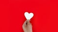 Hand holding a white heart on a red background The meaning of true love is the best wishes for those whom they love, the joy that Royalty Free Stock Photo