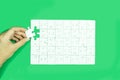 Hand holding white jigsaw puzzle game on green background. Royalty Free Stock Photo