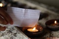 Hand holding a white lined paper note with personal secret prayer. Burn it on a burning candle in a ceramic bowl in the church. Royalty Free Stock Photo