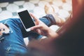 Hand holding white mobile phone with blank black screen on leg with a vintage tile floor in cafe , feeling relax Royalty Free Stock Photo